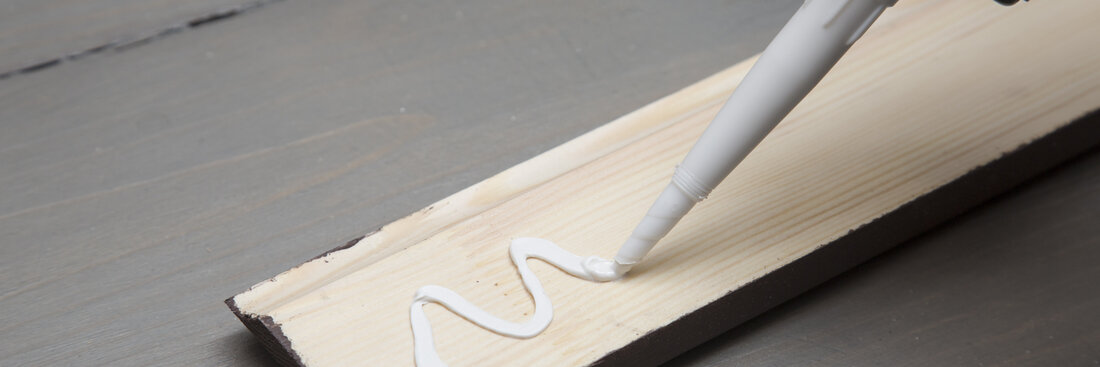 putting glue on a piece of wooden baseboard